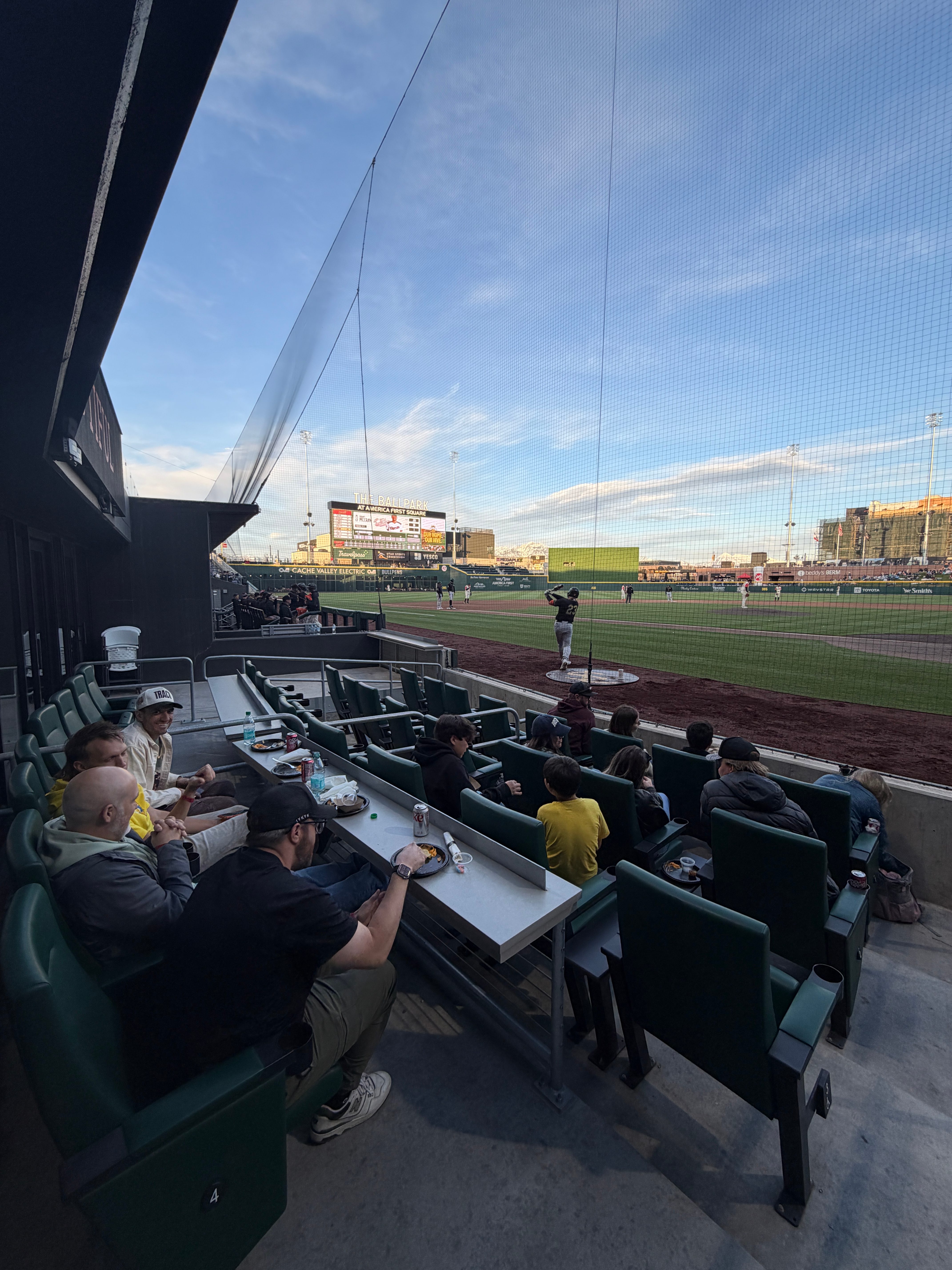 Group seated in premium ballpark seats watching a baseball game at dusk