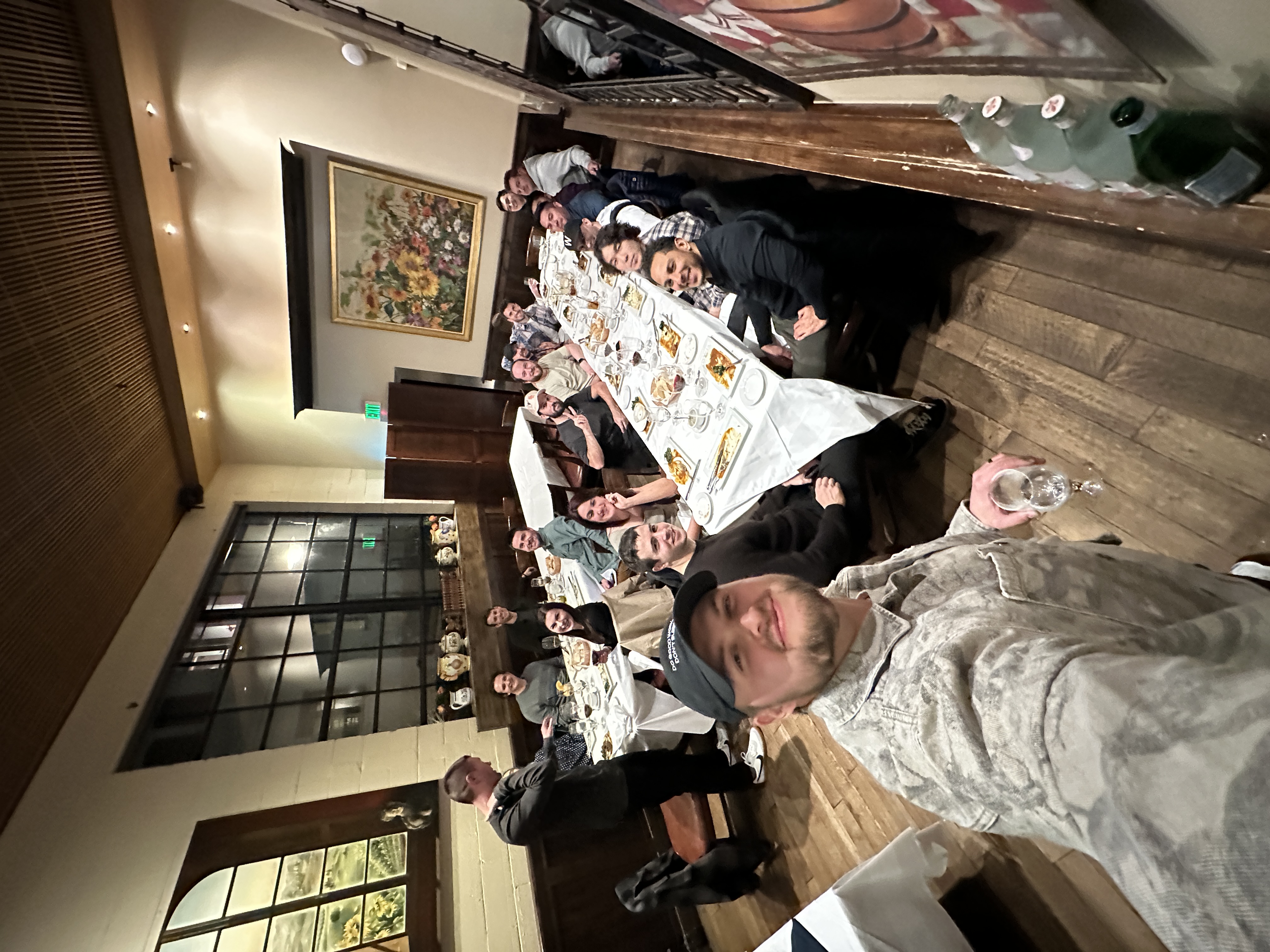 Group dinner selfie at classic restaurant with long communal table and rustic decor