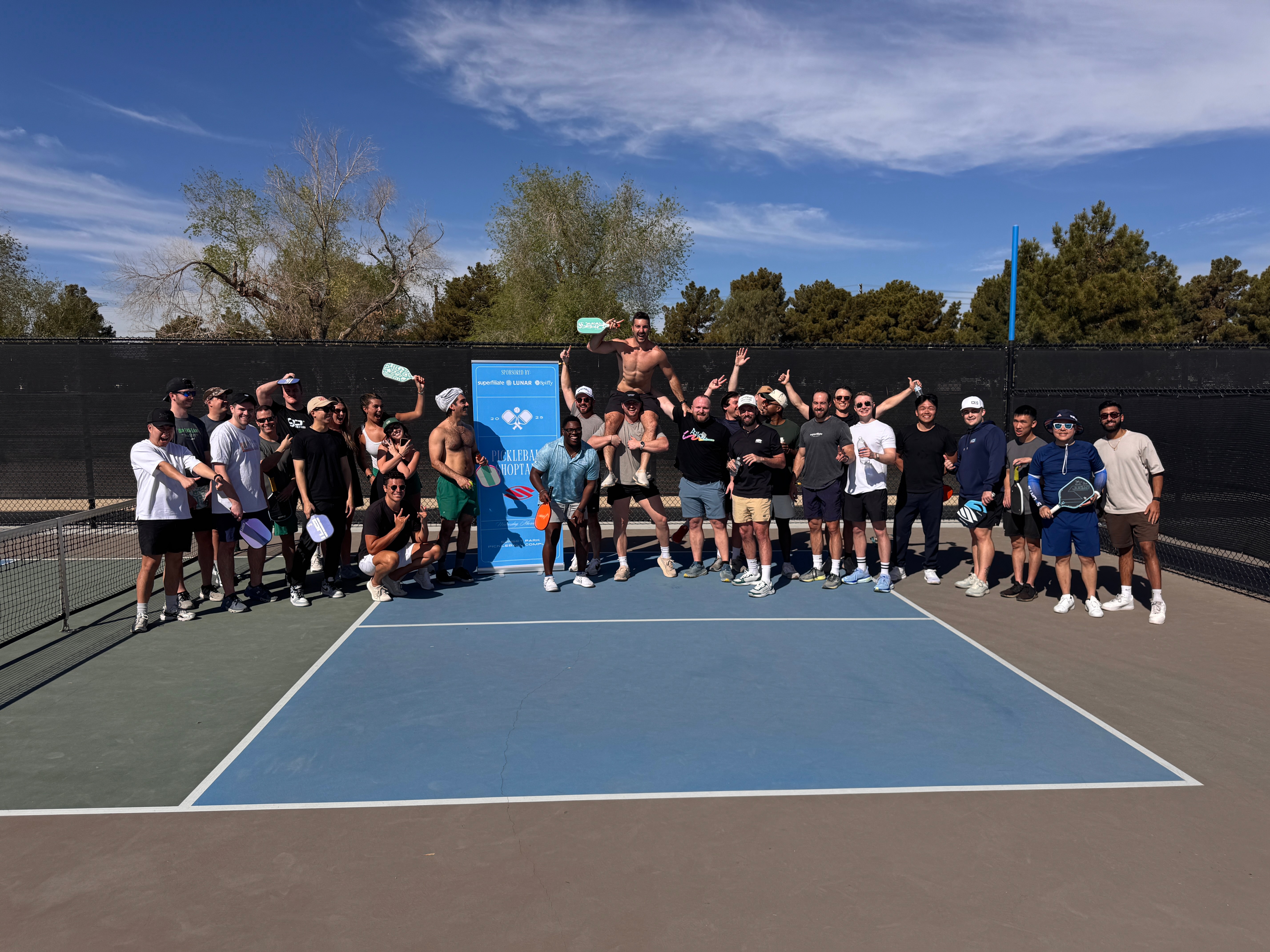 Group photo on outdoor tennis court with tournament banner