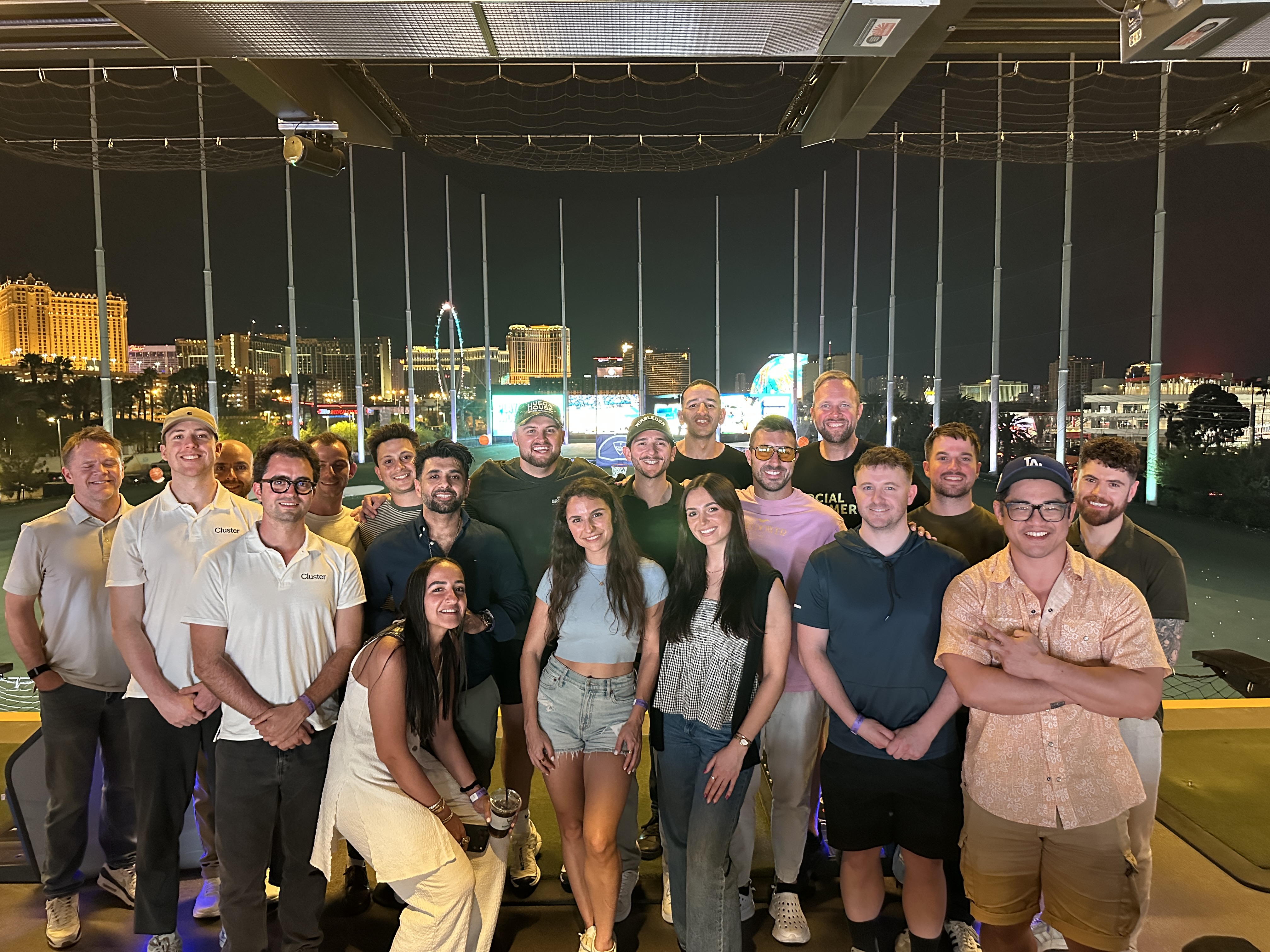 Large group photo at Topgolf with the Las Vegas Strip skyline lit up in the background